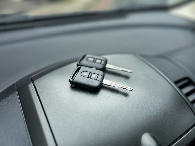 Two car keys sit on a clean dashboard, symbolizing travel and freedom. The scene captures a moment of anticipation for journeys ahead.