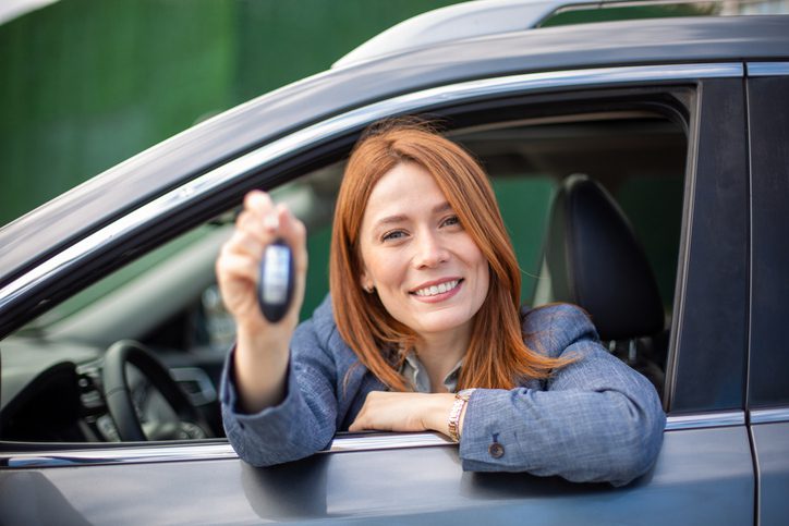 Smiling woman proudly showing car keys from her new vehicle